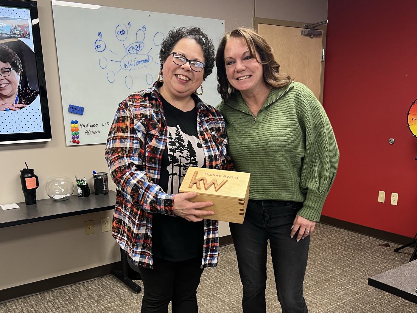 An agent receiving a KW culture award at a team meeting