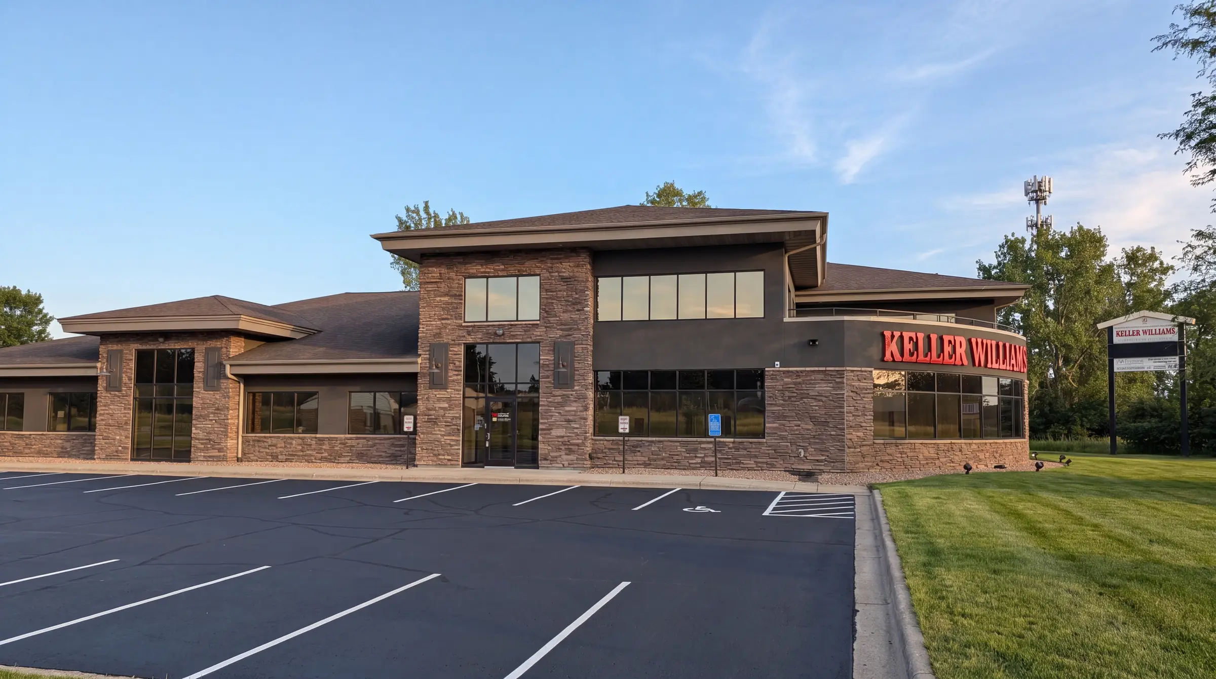 The Keller Williams Classic Realty office in Coon Rapids on a clear afternoon, a stone and glass two-story building seen from the front
