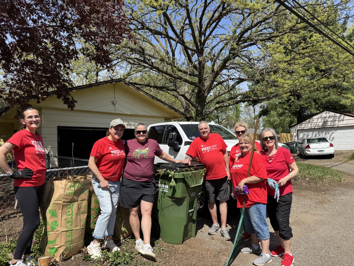 The Keller Williams Classic Realty team in RED Day shirts with bags of yard waste after a north metro neighborhood cleanup